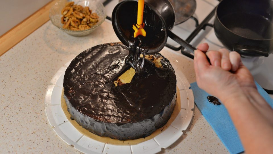 Polevou nejprve potřeme strany dortu a potom vršek. Před zatuhnutím dozdobíme půlkami ořechů