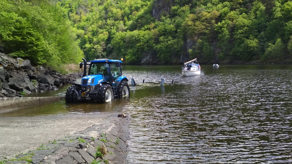 Traktor zacouvá do vody a naloží loď
