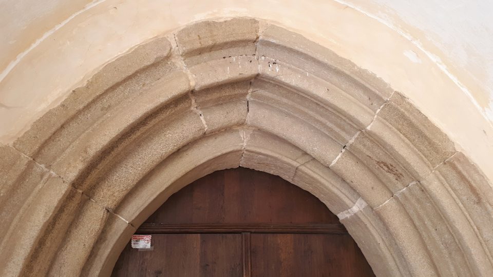 Románské sloupy doplňuje gotický lomený oblouk portálu