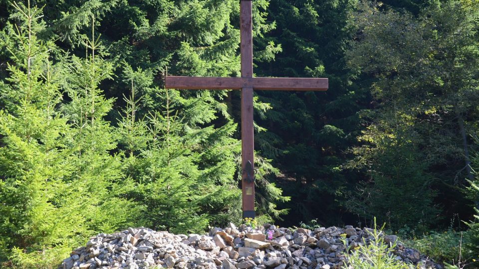 Mohylu tvoří navršené kameny a šest metrů vysoký dřevěný kříž se skautskou lilií