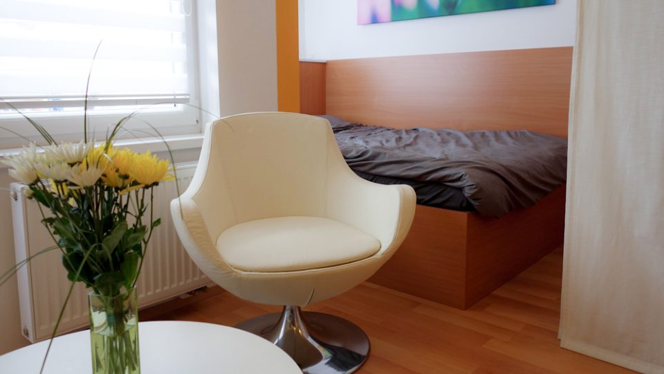 Spací kout vytvoříme oddělením prostorné postele od obývací zóny například pomocí textilních posuvných rolet